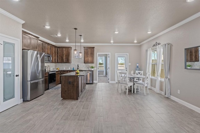 3608 Oglala Trl, Temple, TX 76502 - kitchen with appliances with stainless steel finishes, ornamental molding, tasteful backsplash, a center island, and light wood-type flooring