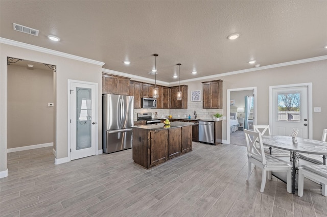 kitchen featuring a kitchen island, appliances with stainless steel finishes, pendant lighting, decorative backsplash, and a textured ceiling