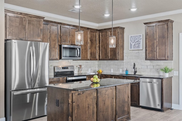 kitchen featuring sink, crown molding, hanging light fixtures, stainless steel appliances, and a center island