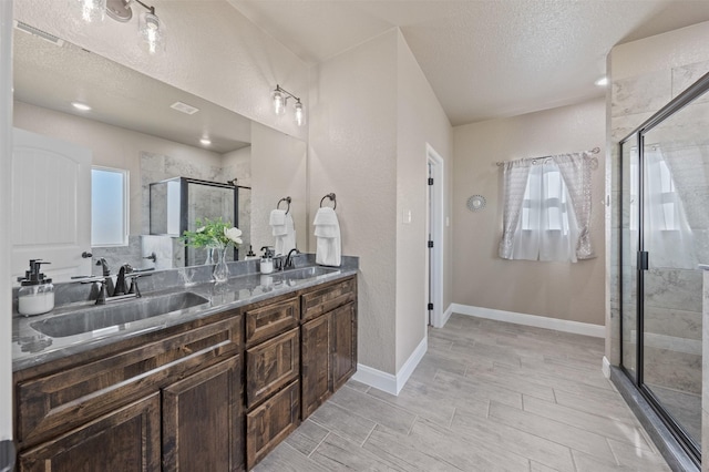 bathroom featuring vanity, a shower with shower door, and a textured ceiling