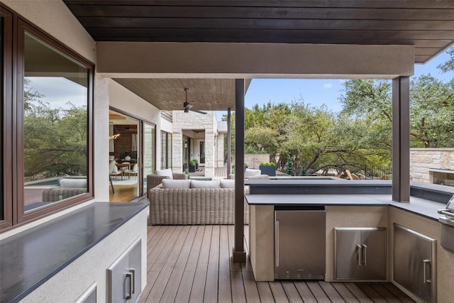 deck featuring an outdoor hangout area, ceiling fan, and an outdoor kitchen