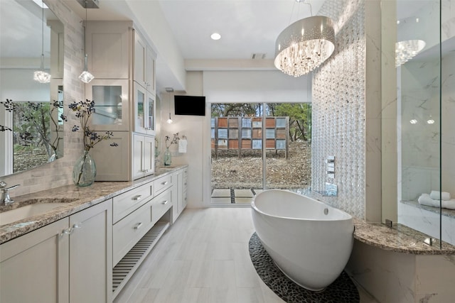 bathroom with a tub to relax in, vanity, and a notable chandelier