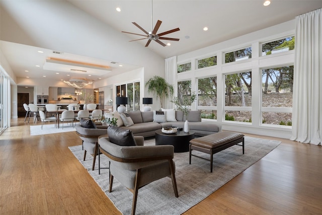 living room with a chandelier, high vaulted ceiling, and light hardwood / wood-style flooring