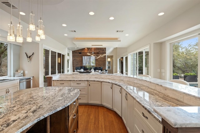 kitchen featuring a kitchen island, hardwood / wood-style floors, pendant lighting, white cabinets, and stainless steel dishwasher