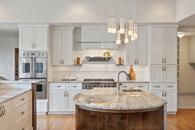 kitchen featuring white cabinetry, stove, double oven, and decorative light fixtures