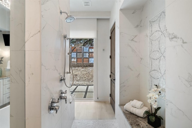 bathroom with wood-type flooring, tile walls, and walk in shower