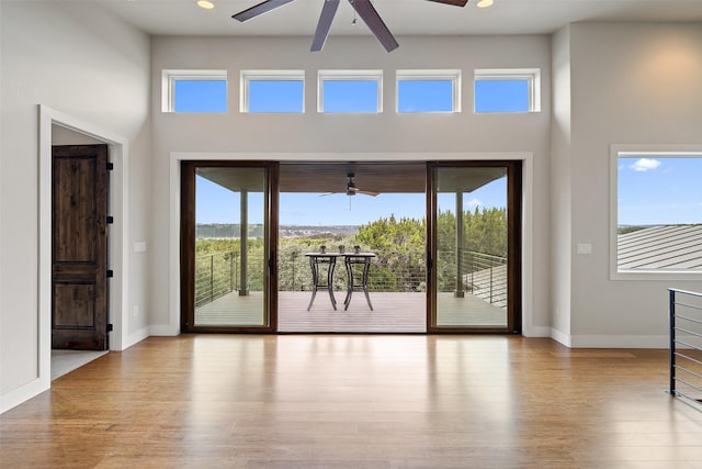 doorway with a towering ceiling, light hardwood / wood-style flooring, and ceiling fan