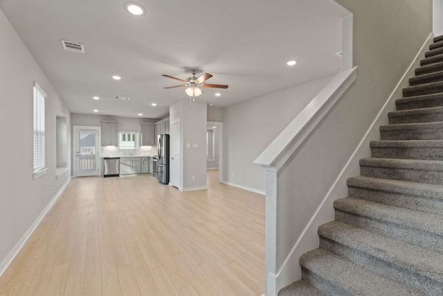 unfurnished living room featuring ceiling fan and light wood-type flooring