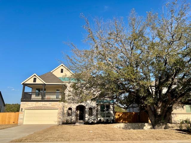 view of front of house with a balcony, an attached garage, fence, and concrete driveway