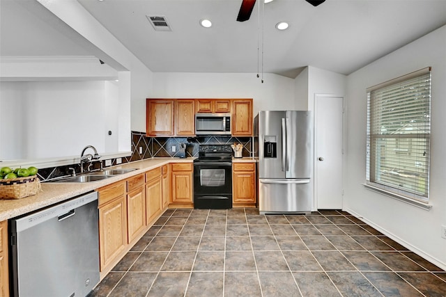 kitchen featuring appliances with stainless steel finishes, sink, dark tile patterned flooring, decorative backsplash, and ceiling fan