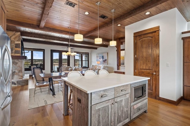 kitchen with decorative light fixtures, light hardwood / wood-style flooring, stainless steel appliances, and a kitchen island