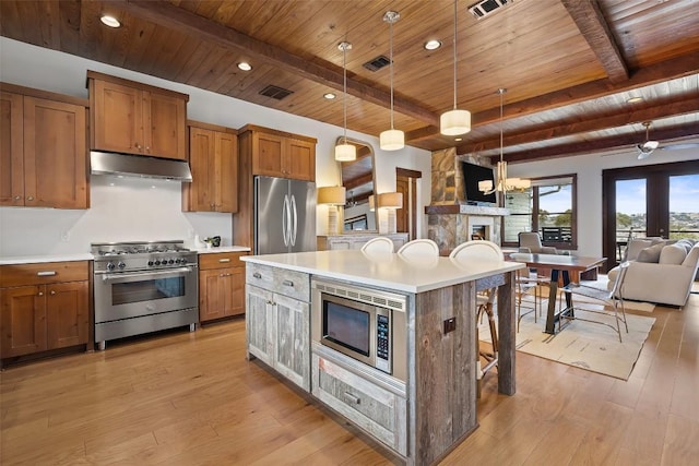 kitchen with a breakfast bar, decorative light fixtures, a center island, wooden ceiling, and appliances with stainless steel finishes