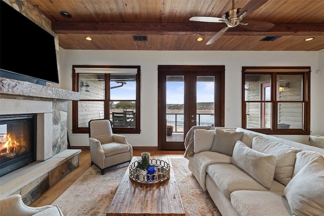 living room with beamed ceiling, wooden ceiling, a fireplace, and light wood-type flooring