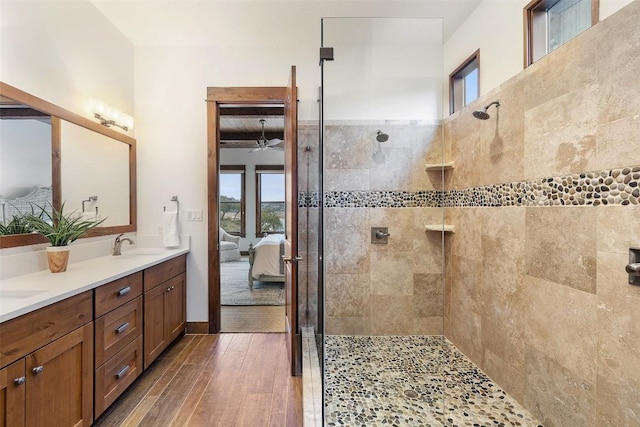 bathroom featuring wood-type flooring, a tile shower, and vanity