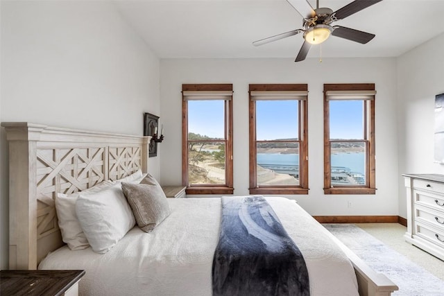 carpeted bedroom featuring ceiling fan and a water view