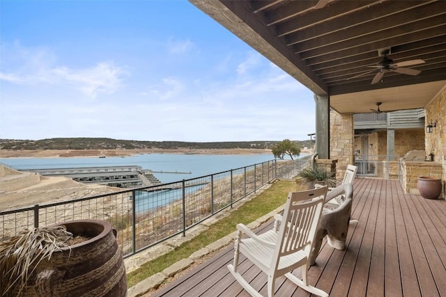 deck with a water view and ceiling fan