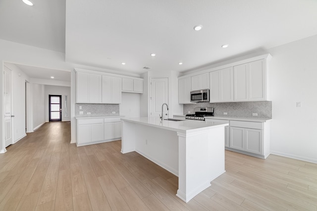 kitchen featuring a sink, stainless steel appliances, white cabinetry, and light wood finished floors