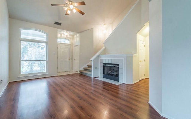 unfurnished living room featuring ceiling fan, a tiled fireplace, and hardwood / wood-style floors