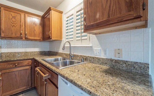 kitchen with sink, decorative backsplash, light tile patterned floors, light stone counters, and white dishwasher