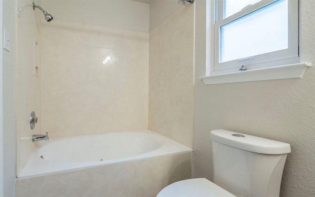 bathroom featuring tiled shower / bath combo and toilet