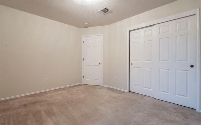 unfurnished bedroom featuring light carpet and a closet