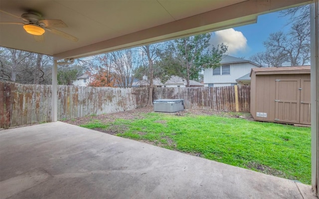 view of yard featuring ceiling fan, a storage unit, a hot tub, and a patio