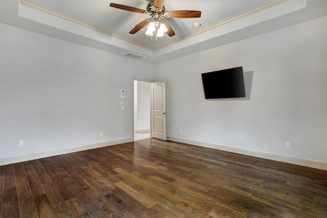 empty room with hardwood / wood-style flooring, ceiling fan, ornamental molding, and a tray ceiling