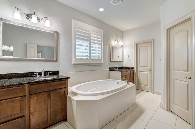 bathroom featuring vanity, tiled tub, and tile patterned flooring