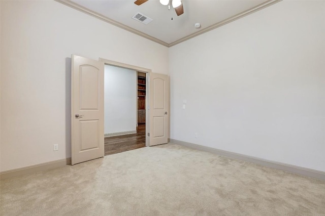 unfurnished bedroom featuring crown molding, light colored carpet, and ceiling fan