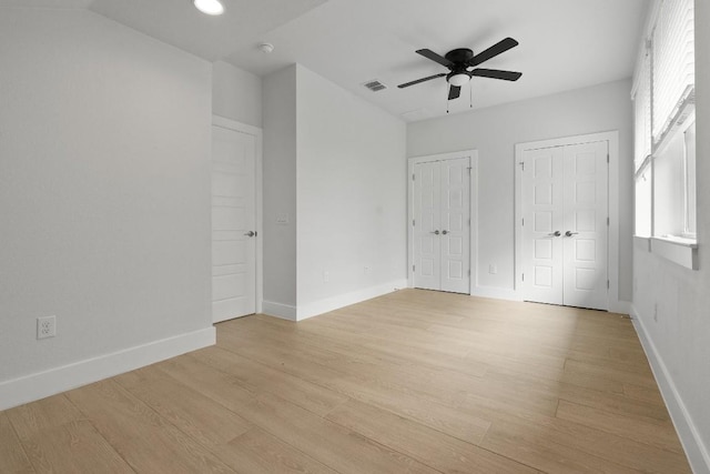 unfurnished bedroom featuring two closets, ceiling fan, and light hardwood / wood-style flooring