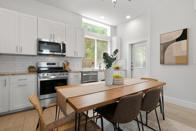 kitchen with light stone counters, backsplash, stainless steel appliances, and white cabinets