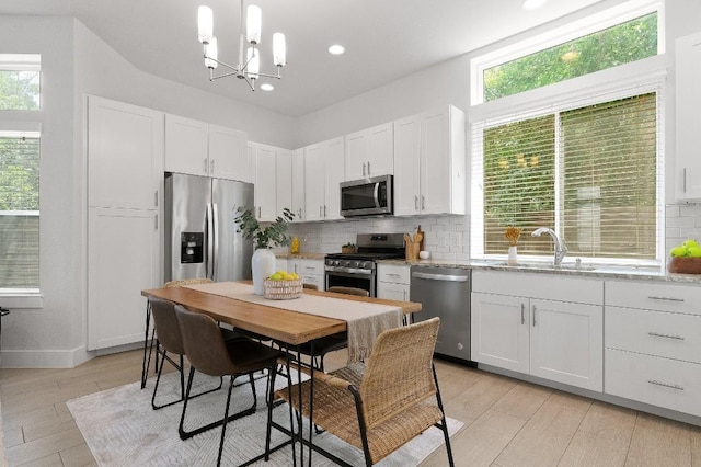 kitchen featuring white cabinetry, decorative light fixtures, decorative backsplash, and appliances with stainless steel finishes