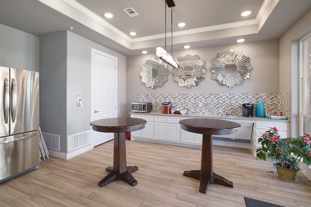 104 Bella Toscana Ave Unit 2211, Lakeway, TX 78734 - kitchen with stainless steel appliances, a raised ceiling, crown molding, white cabinets, and backsplash
