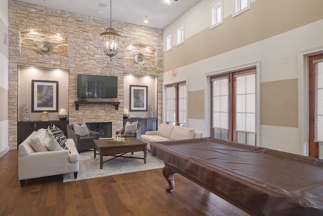 playroom with a towering ceiling, a stone fireplace, and hardwood / wood-style floors