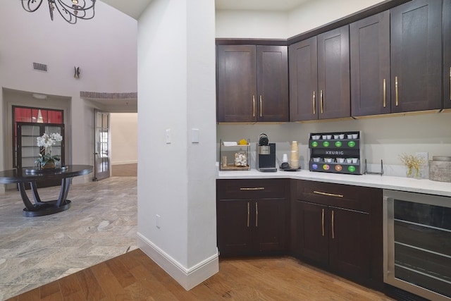 kitchen featuring beverage cooler, dark brown cabinetry, and light hardwood / wood-style floors