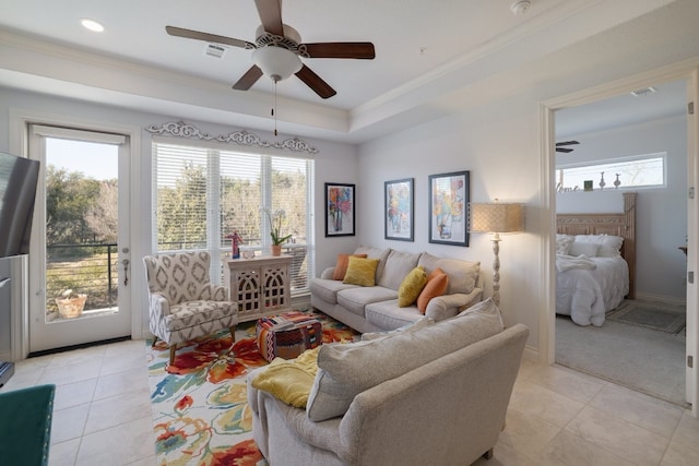 tiled living room featuring crown molding, a healthy amount of sunlight, ceiling fan, and a tray ceiling