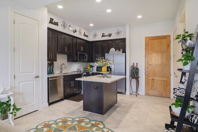 kitchen featuring a kitchen island, sink, decorative backsplash, stainless steel appliances, and dark brown cabinets