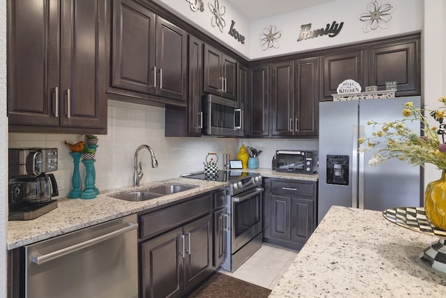 kitchen with dark brown cabinetry, sink, light tile patterned floors, stainless steel appliances, and decorative backsplash