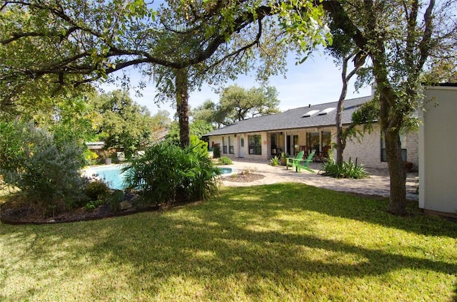 rear view of house featuring a patio, an outdoor pool, and a lawn