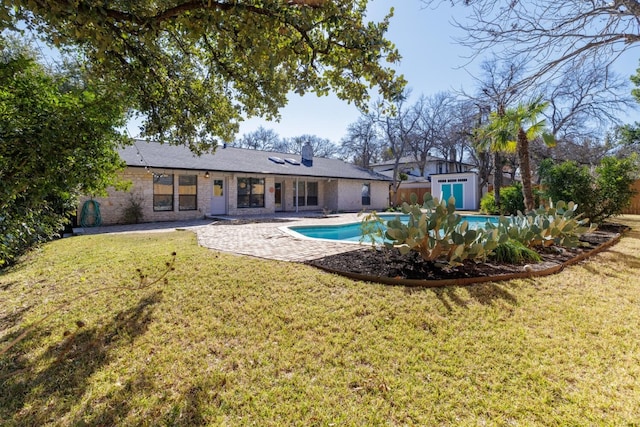 back of property featuring an outdoor pool, an outbuilding, a lawn, and a patio