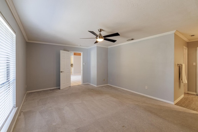 empty room featuring crown molding, a ceiling fan, visible vents, and light carpet