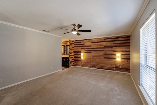 unfurnished room featuring ceiling fan, carpet floors, wooden walls, and ornamental molding