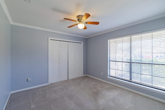 unfurnished bedroom with crown molding, carpet flooring, baseboards, and a closet