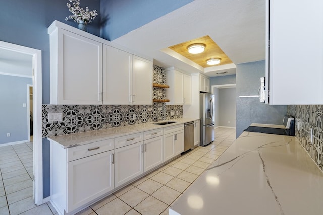 kitchen featuring a tray ceiling, light tile patterned flooring, white cabinets, stainless steel appliances, and open shelves