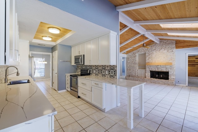 kitchen featuring open floor plan, light tile patterned floors, white cabinets, stainless steel appliances, and a sink