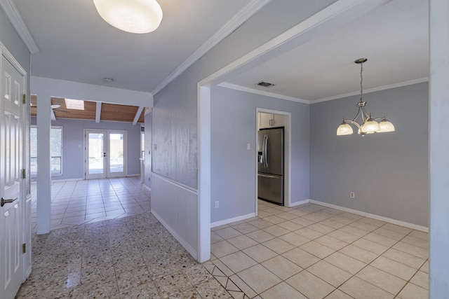 spare room featuring visible vents, a chandelier, ornamental molding, and french doors