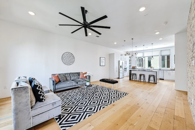 living room with ceiling fan and light hardwood / wood-style flooring