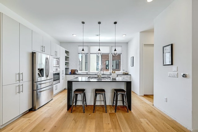 kitchen featuring white cabinetry, appliances with stainless steel finishes, decorative light fixtures, and a center island