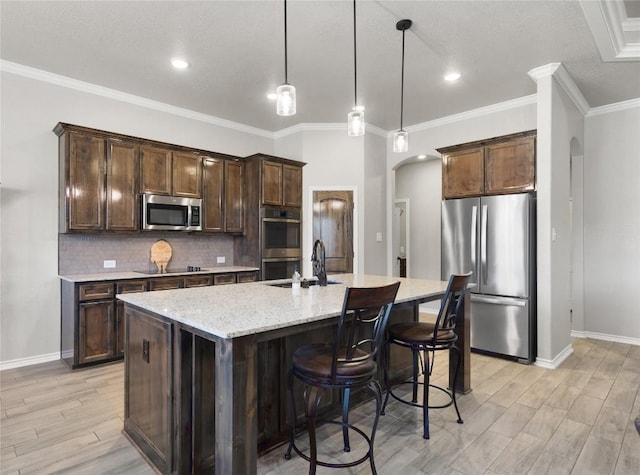 5204 La Terraza Ln, Killeen, TX 76549 - kitchen featuring appliances with stainless steel finishes, arched walkways, dark brown cabinets, light wood-style floors, and ornamental molding