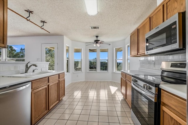 kitchen featuring sink, light tile patterned floors, plenty of natural light, stainless steel appliances, and tasteful backsplash